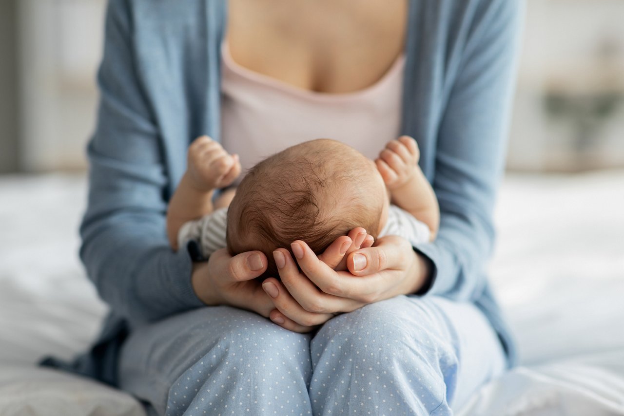 Mutter hält Neugeborenes auf Schoß fest