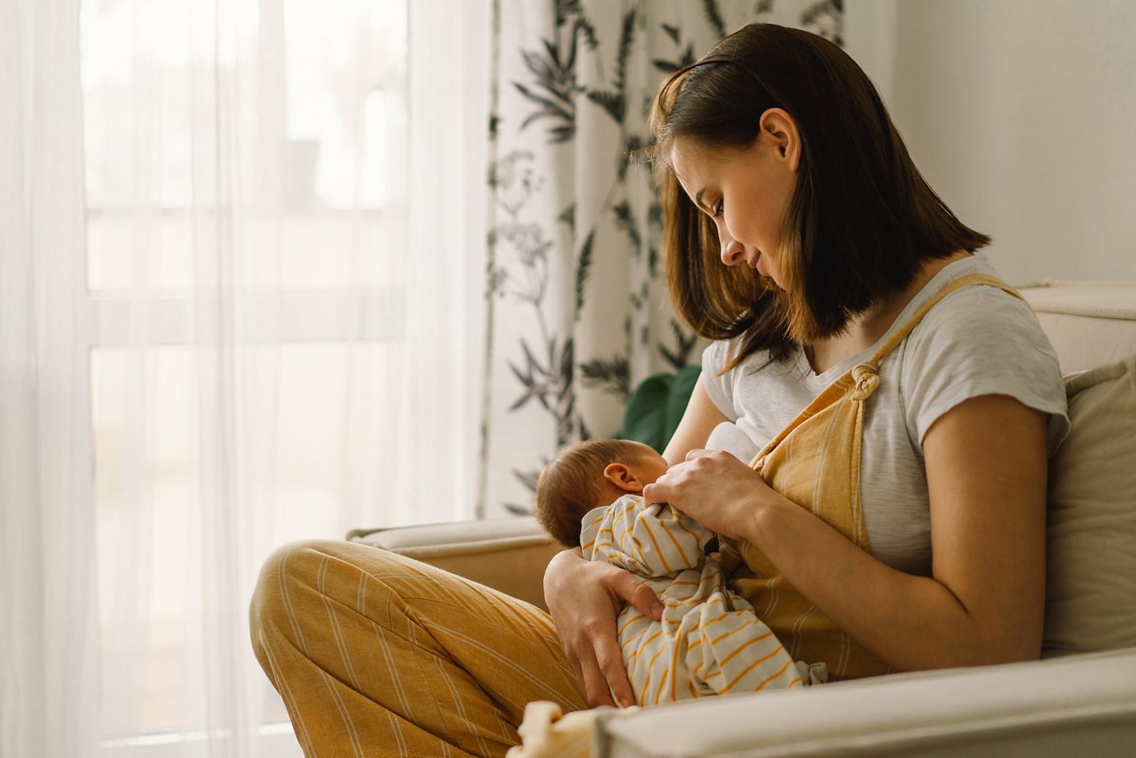 Newborn baby boy sucking milk from mothers breast. Portrait of mom and breastfeeding baby. Concept of healthy and natural baby breastfeeding nutrition.