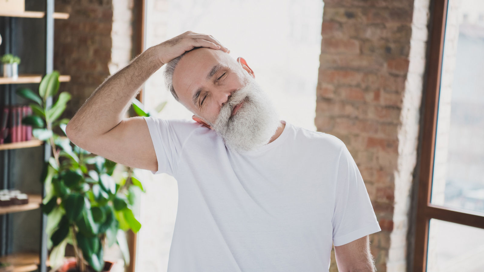 Photo of handsome smiling good mood grandfather stretching neck with closed eyes exercising at home quarantine,Photo of handsome smiling good mood grandfather stretching neck 