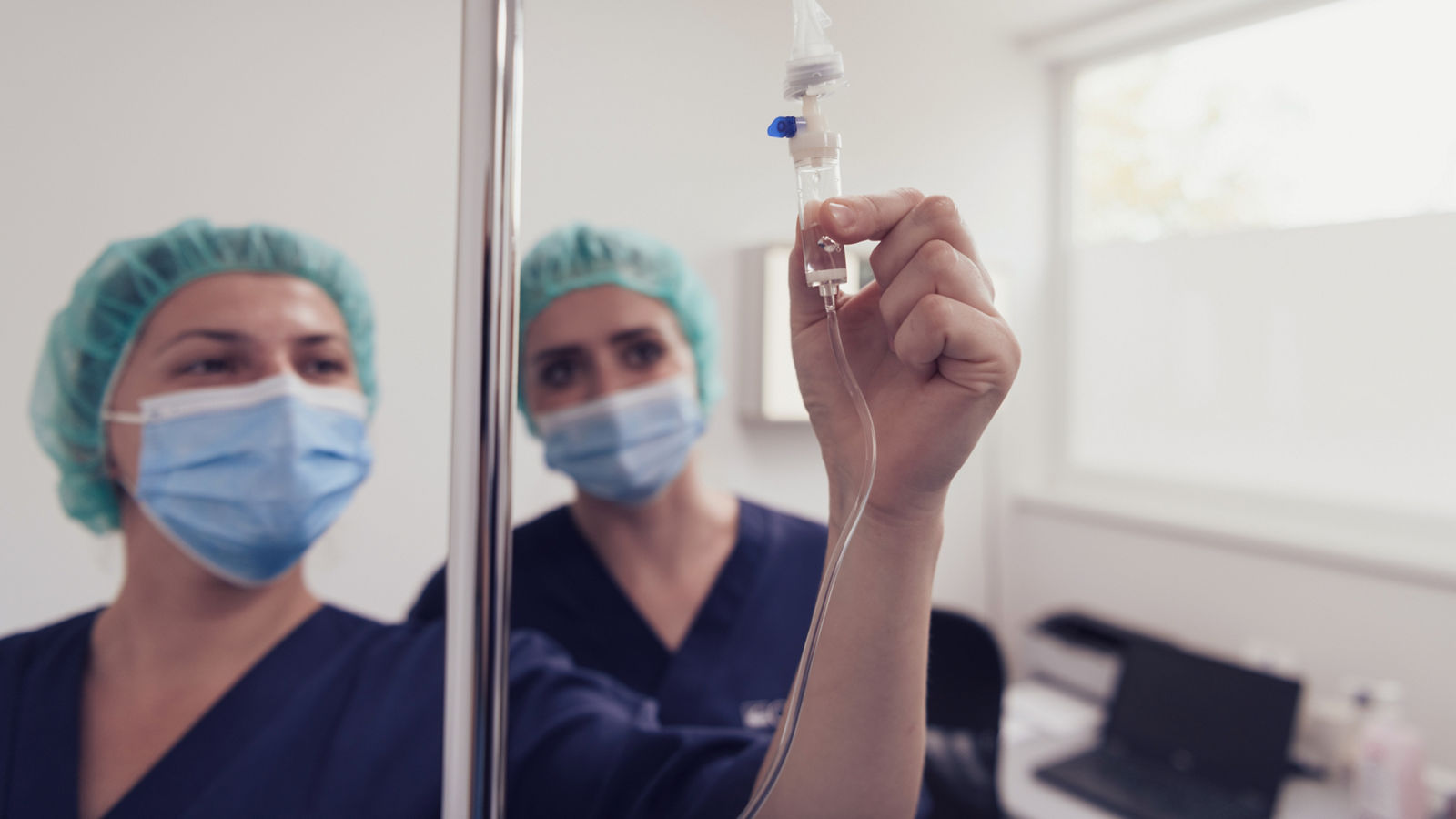 General practitioner holding intravenous drip infusion. Doctor handling IV fluid drip with copy space on white background. Nurse performing Intravenous therapy.