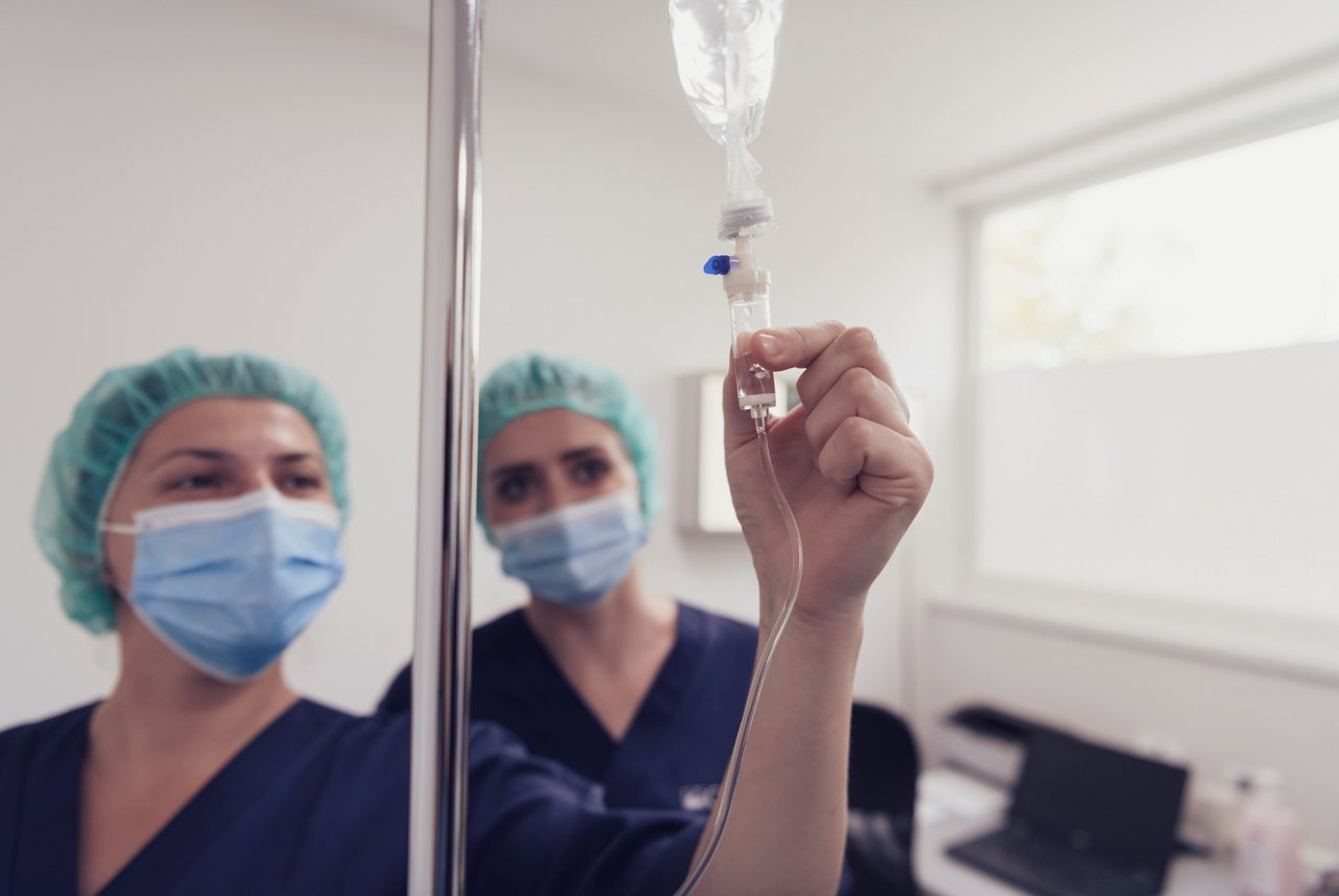 General practitioner holding intravenous drip infusion. Doctor handling IV fluid drip with copy space on white background.Nurse Team performing Intravenous therapy. High quality photo.Selective focus.