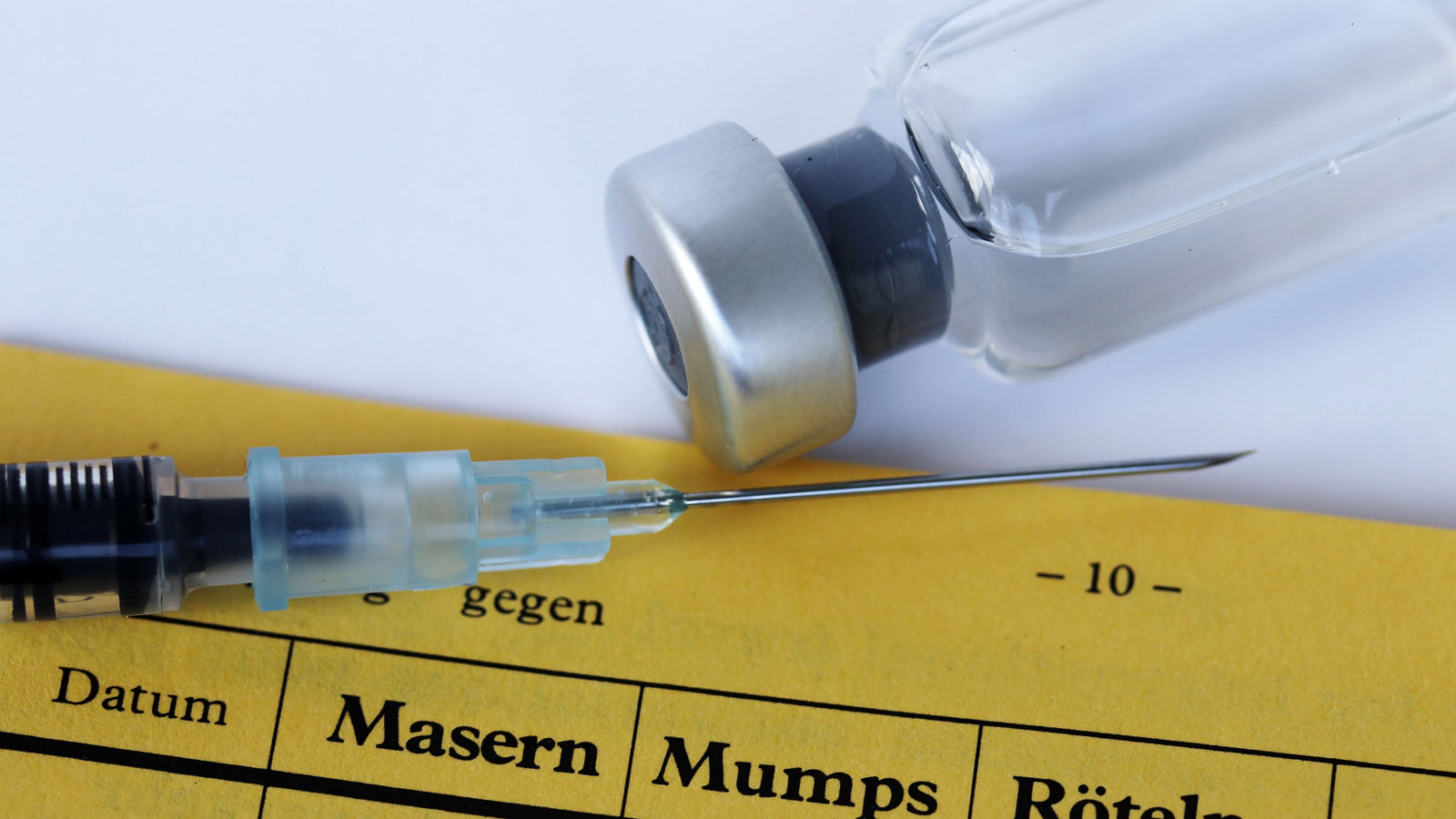 Impfung gegen Masern, Mumps und Röteln mit Impfpass, Spritze und Impfstoff