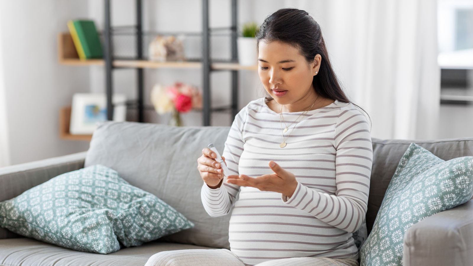 pregnant woman with glucometer making blood test