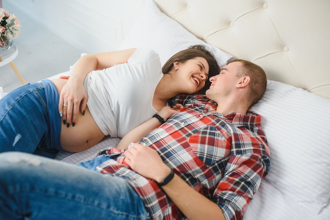 Young pregnant woman with husband on sofa in room