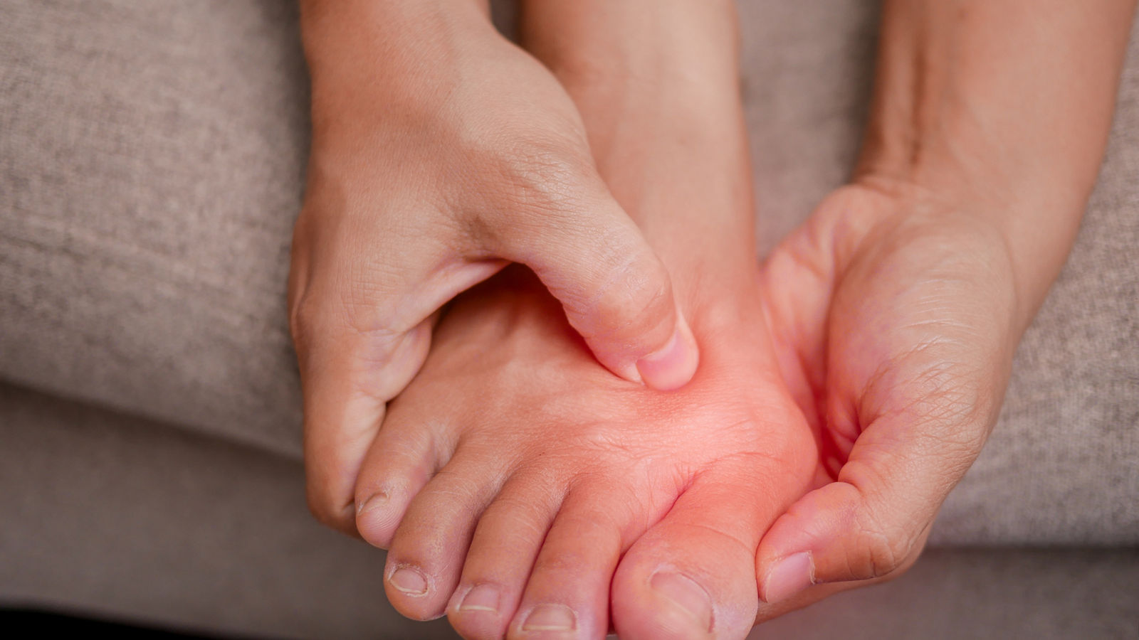 Closeup of female holding her painful feet and massaging her bunion toes to relieve pain. Swollen bunion at the edge of the big toe causes deformity (Hallux valgus). Woman's health concept.,Closeup of female holding her painful feet and massaging her bun