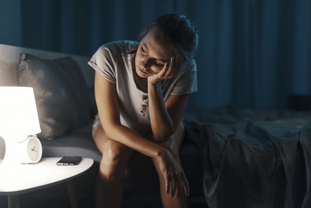 Exhausted woman suffering from insomnia, she is sitting on the bed and thinking