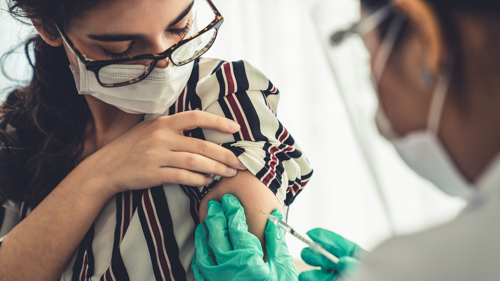 Young woman visits skillful doctor at hospital for vaccination