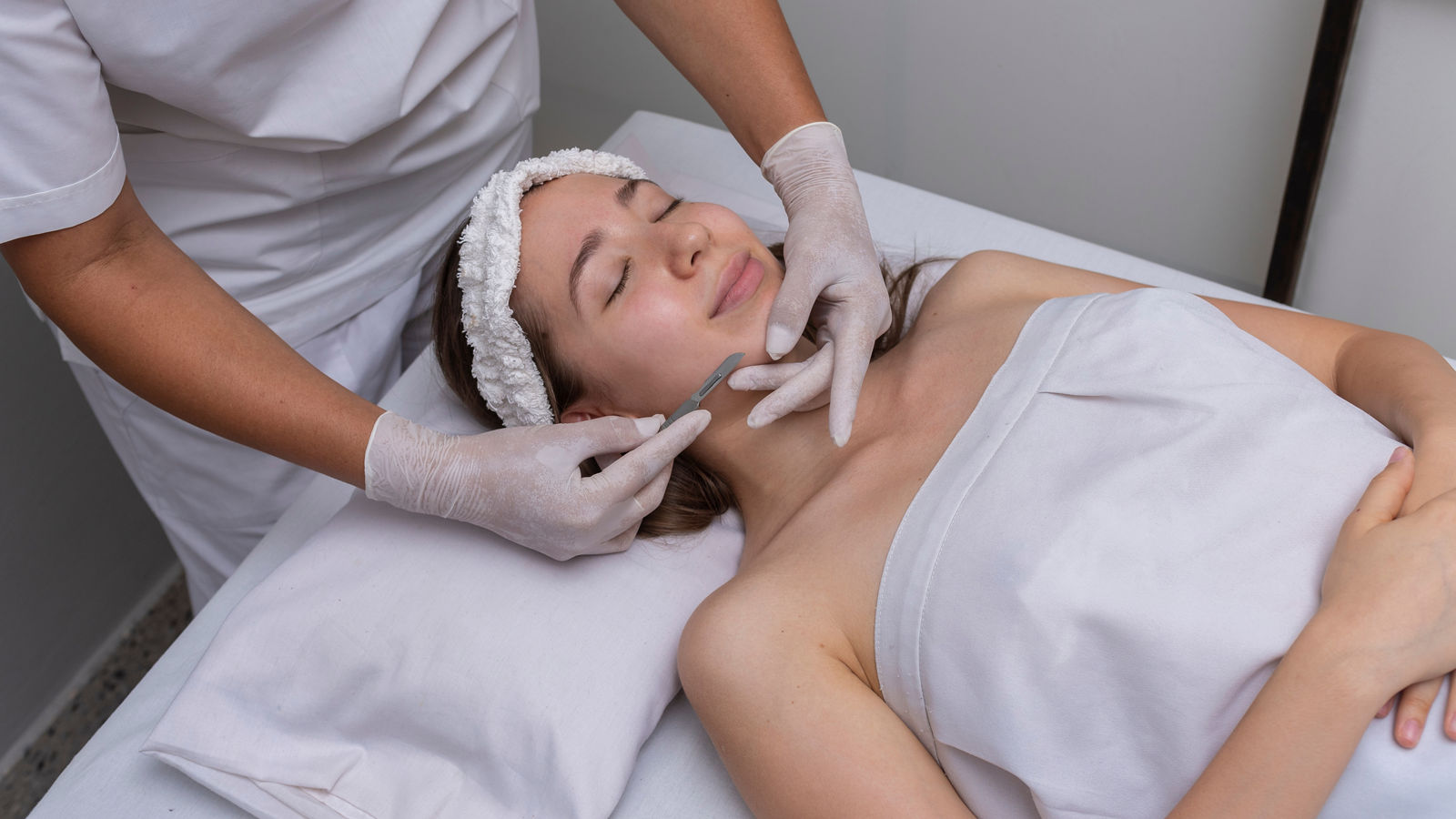 young woman lying on a stretcher in an aesthetic center performing beauty treatment and facial aesthetics with dermapen and dermaplaning techniques