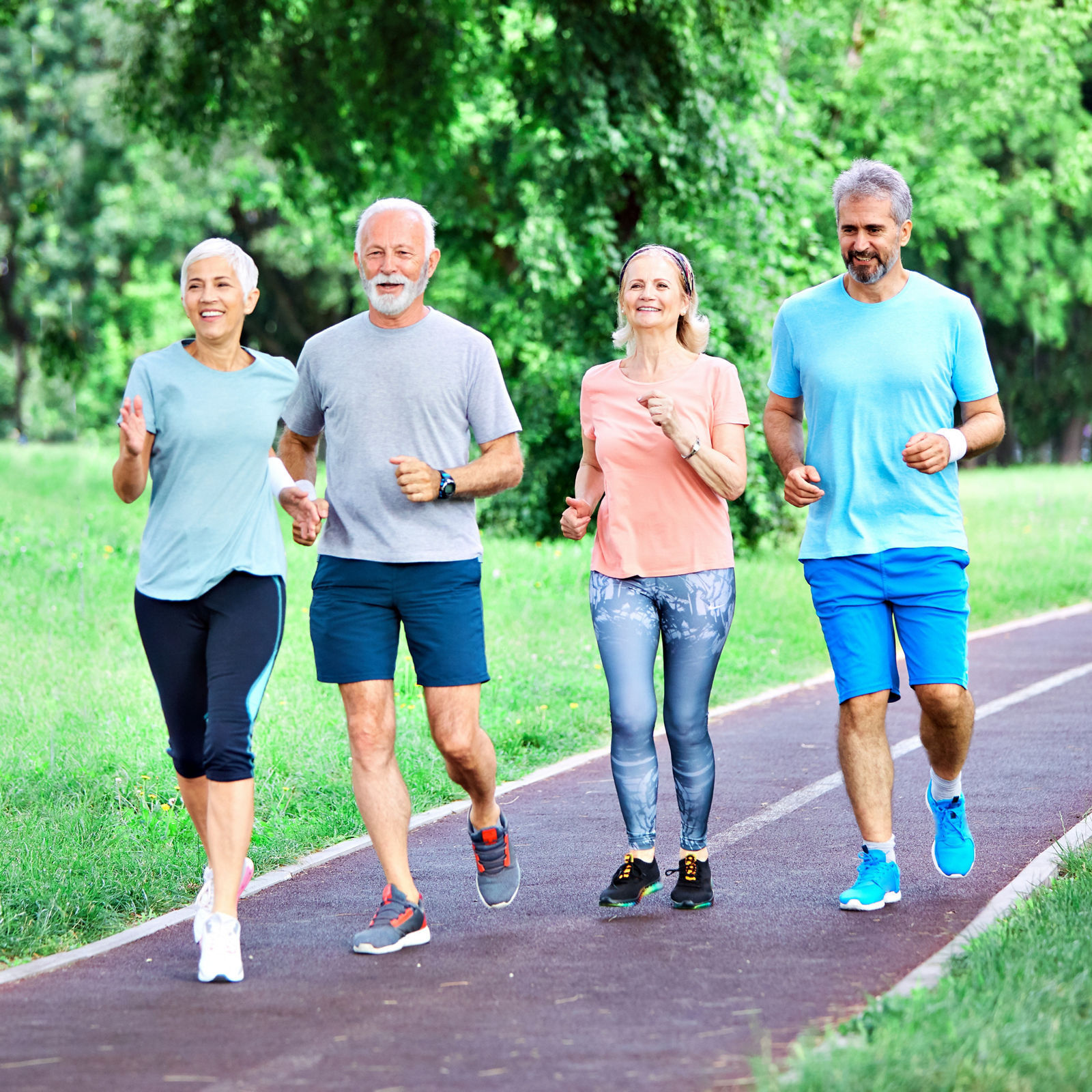 Smiling active senior people jogging together in the park