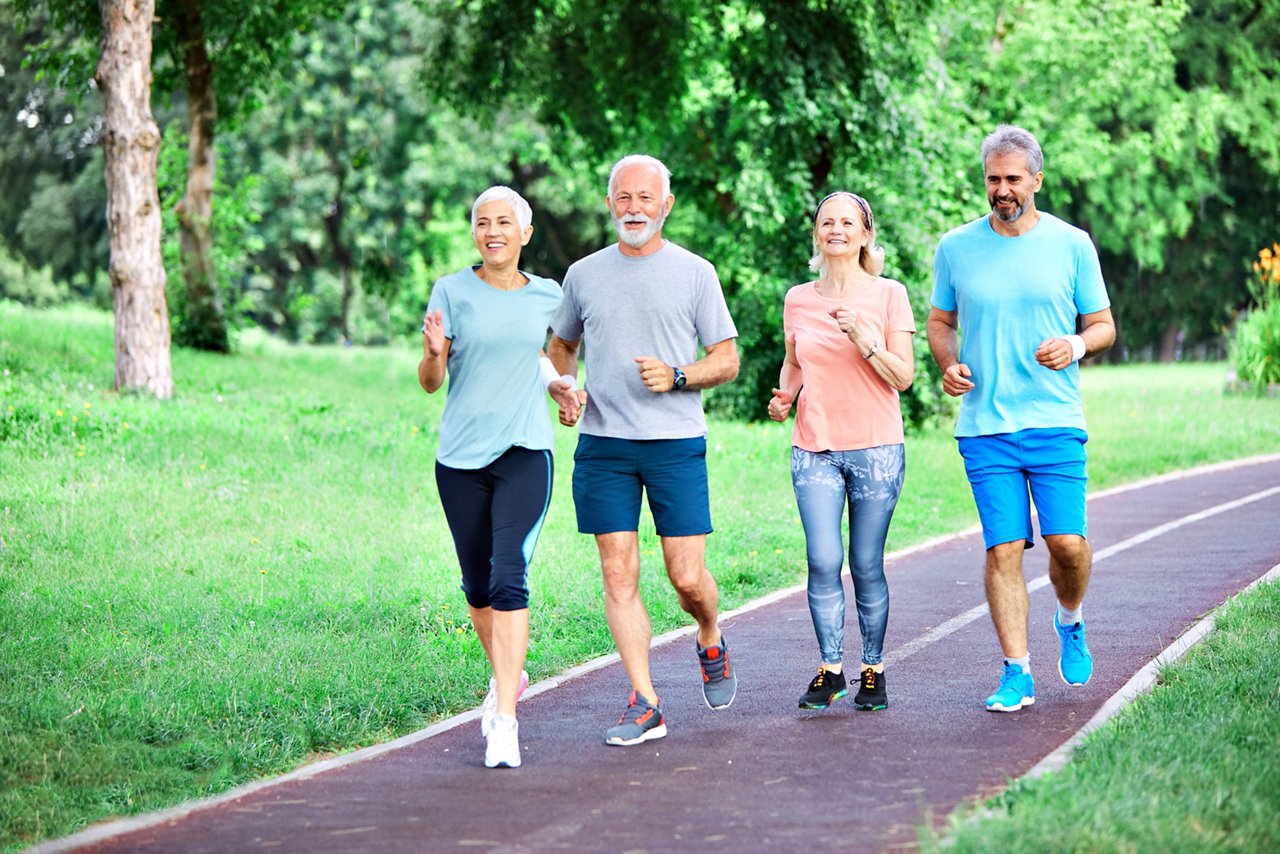 Smiling active senior people jogging together in the park