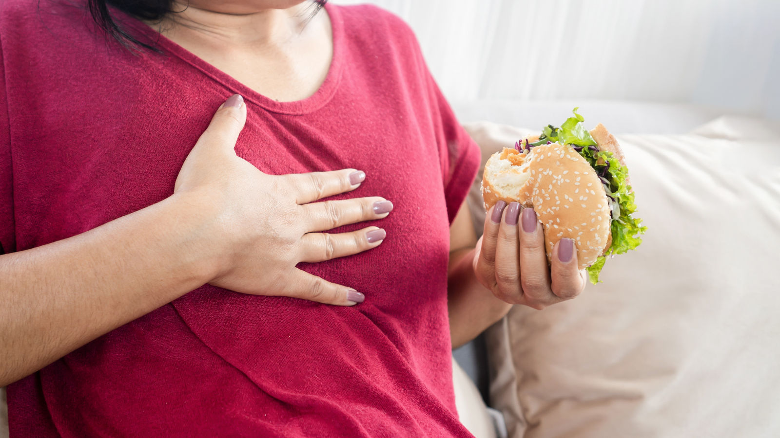 woman having Gastroesophageal reflux disease after eating a burger,woman having Gastroesophageal reflux disease after eating a burg