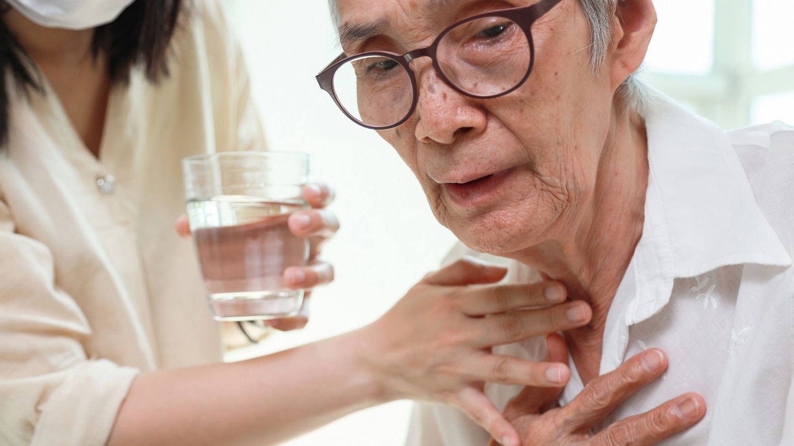 Asian senior woman coughing choking while drinking water or eating food,danger or risk of lung infection,disease of silent aspiration pneumonia,old elderly patient choking water after taking the pills
