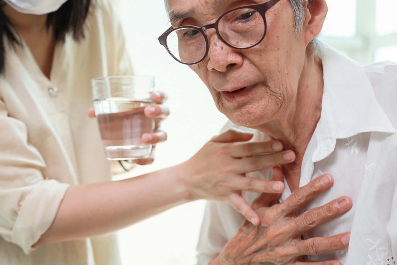 Asian senior woman coughing choking while drinking water or eating food,danger or risk of lung infection,disease of silent aspiration pneumonia,old elderly patient choking water after taking the pills