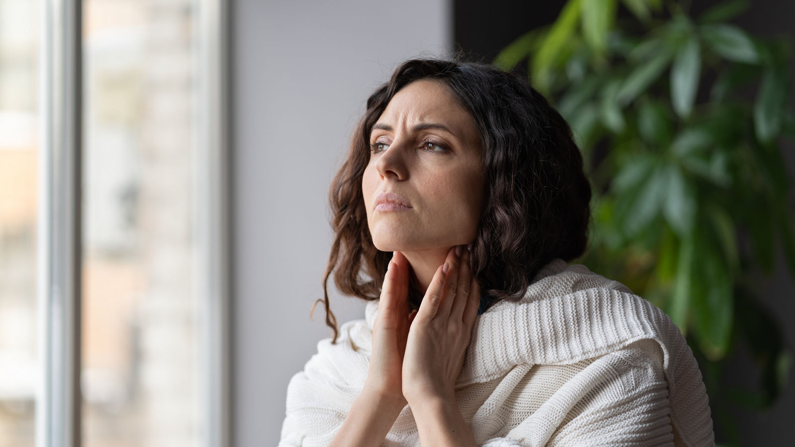 Young sick unhealthy looking woman suffering from sore throat and swollen glands, looking out window,Young sick unhealthy looking woman suffering from sore throat an