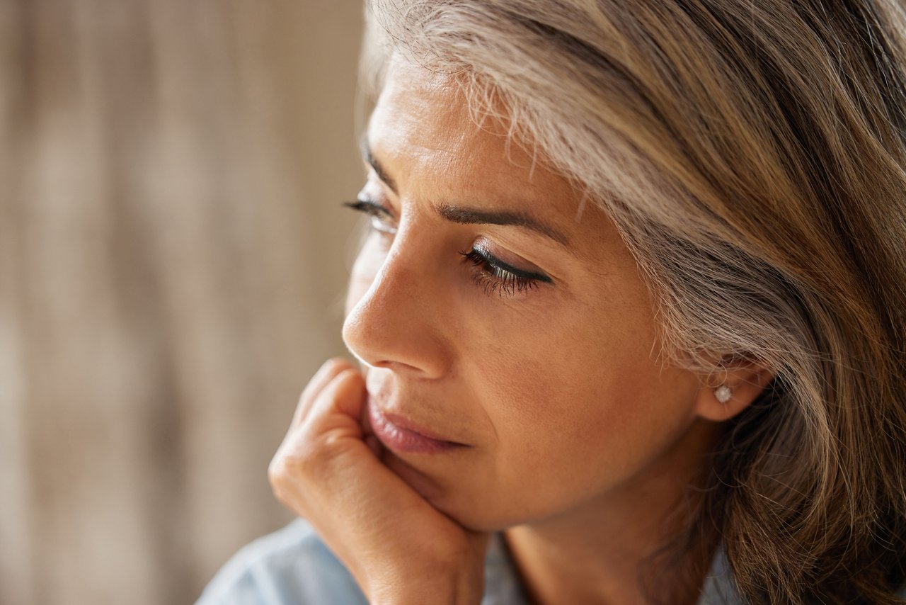 Close Up Shot Of Thoughtful Mature Woman Looking Out Of Window At Home