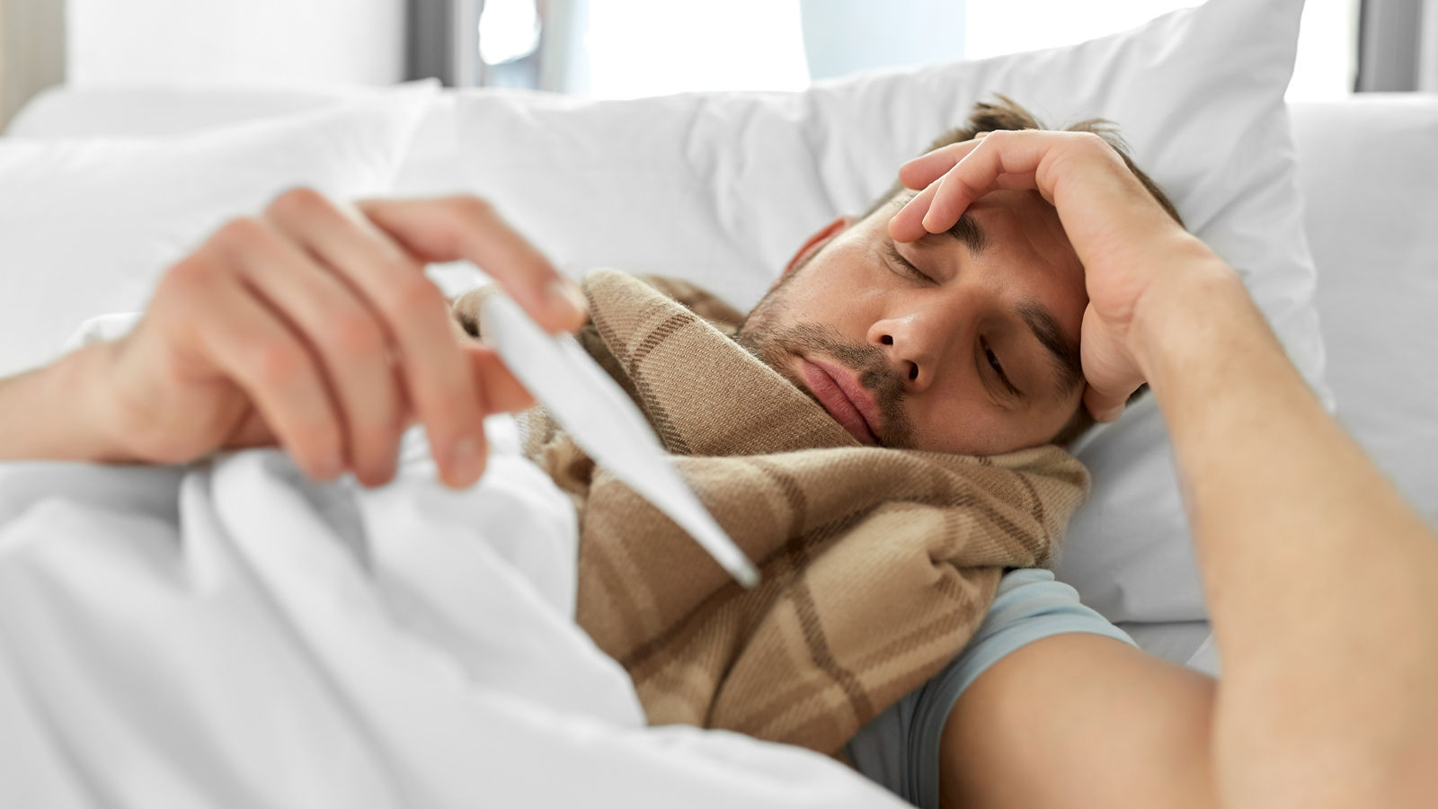 sick man measuring temperature by thermometer