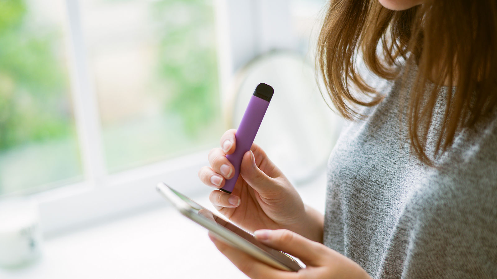 Junge Teenagerin mit Vape am Handy