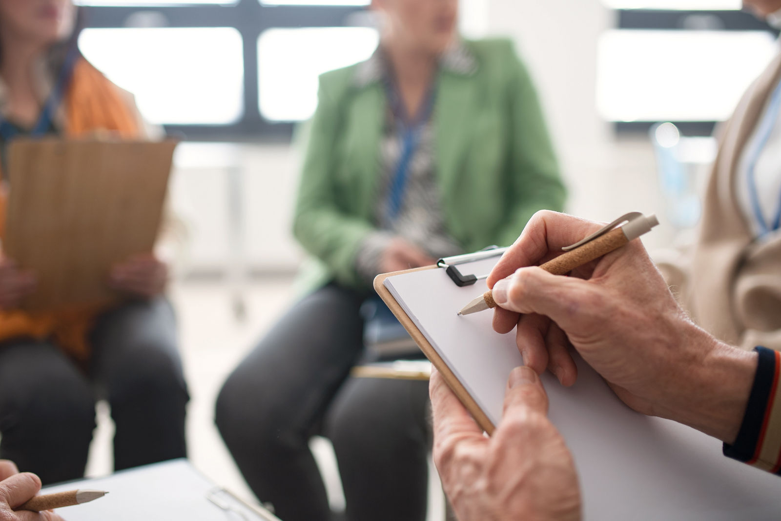 Elderly people attending a group therapy session at nursing house, sitting in circle, having conversation with psychologist, close-up