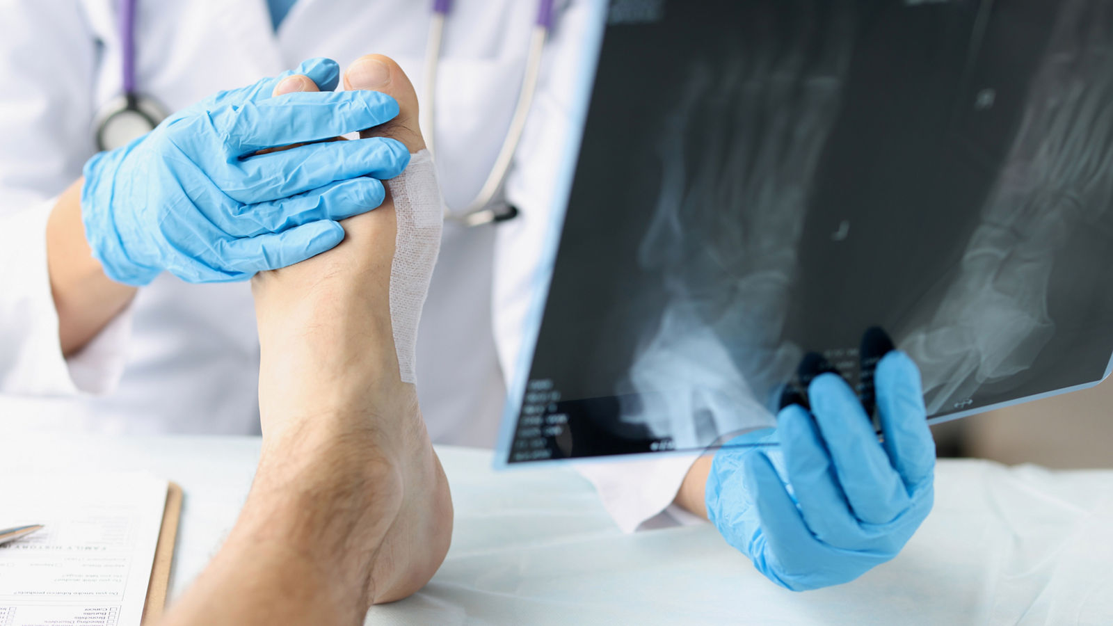 Traumatologist looking at xray of foot and examining patient