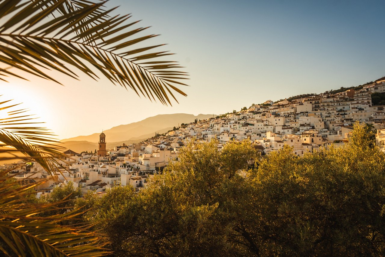 Das malerische Bergdorf Cómpeta in Andalusien bei Sonnenuntergang. Die weißen Häuser strahlen im warmen Licht, umgeben von atemberaubender Natur und Bergen.
