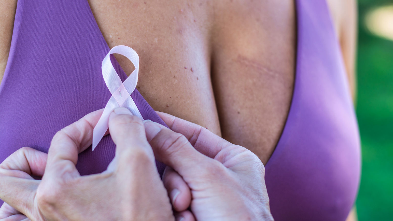 Breast Cancer Awareness Day. Anonymous woman attaches a symbol of Awareness and the fight against breast cancer to the clothes of another unrecognizable woman. Breast Cancer Awareness Day concept.Sign