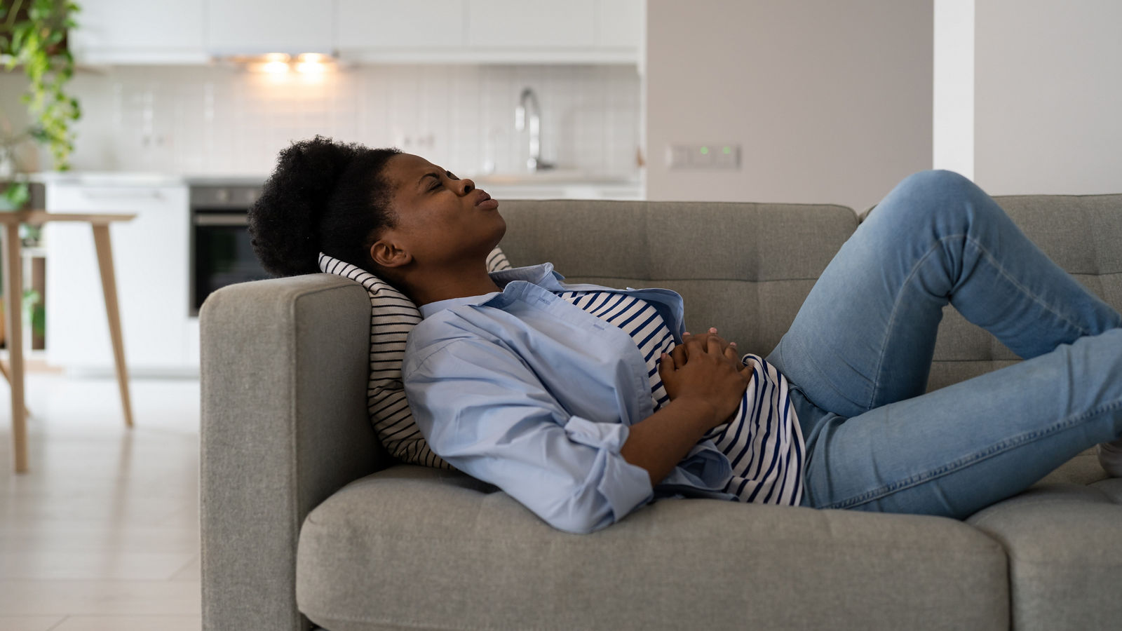 Diseased African American woman holding stomach feeling pain and anguish after food poisoning