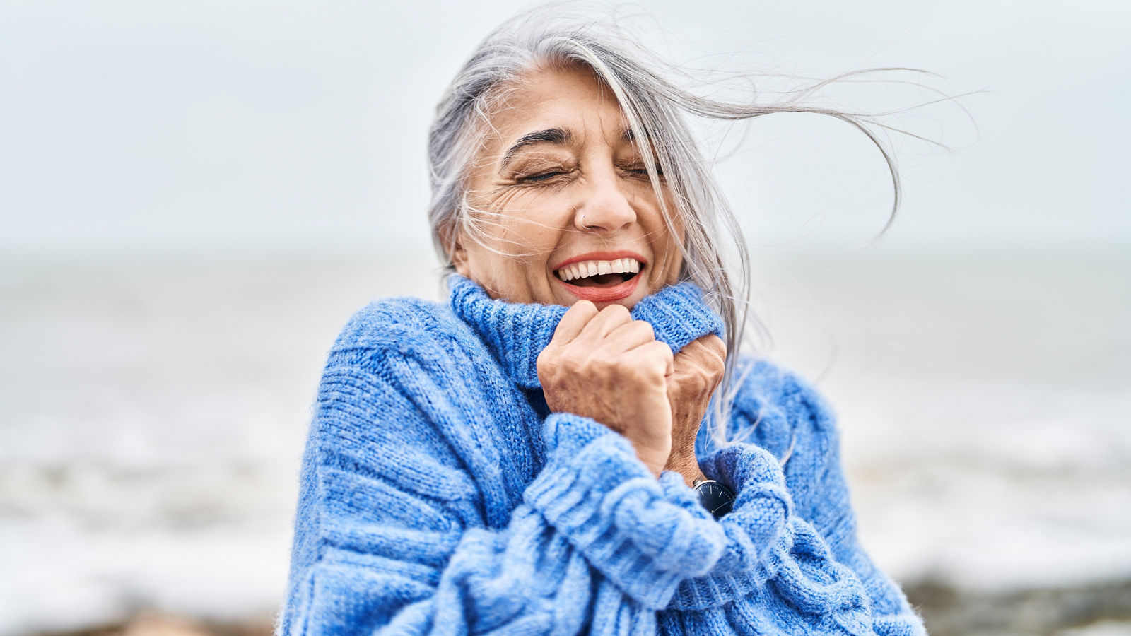 Middle age grey-haired woman smiling confident standing at seaside