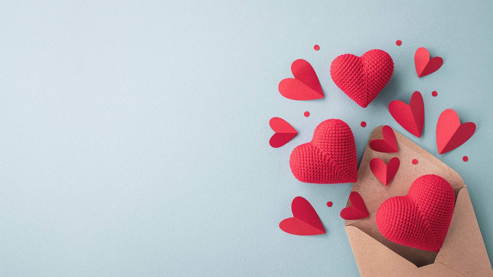 Saint Valentine day holiday background with envelope, knitted and paper red hearts for love romantic message. Flat lay composition..