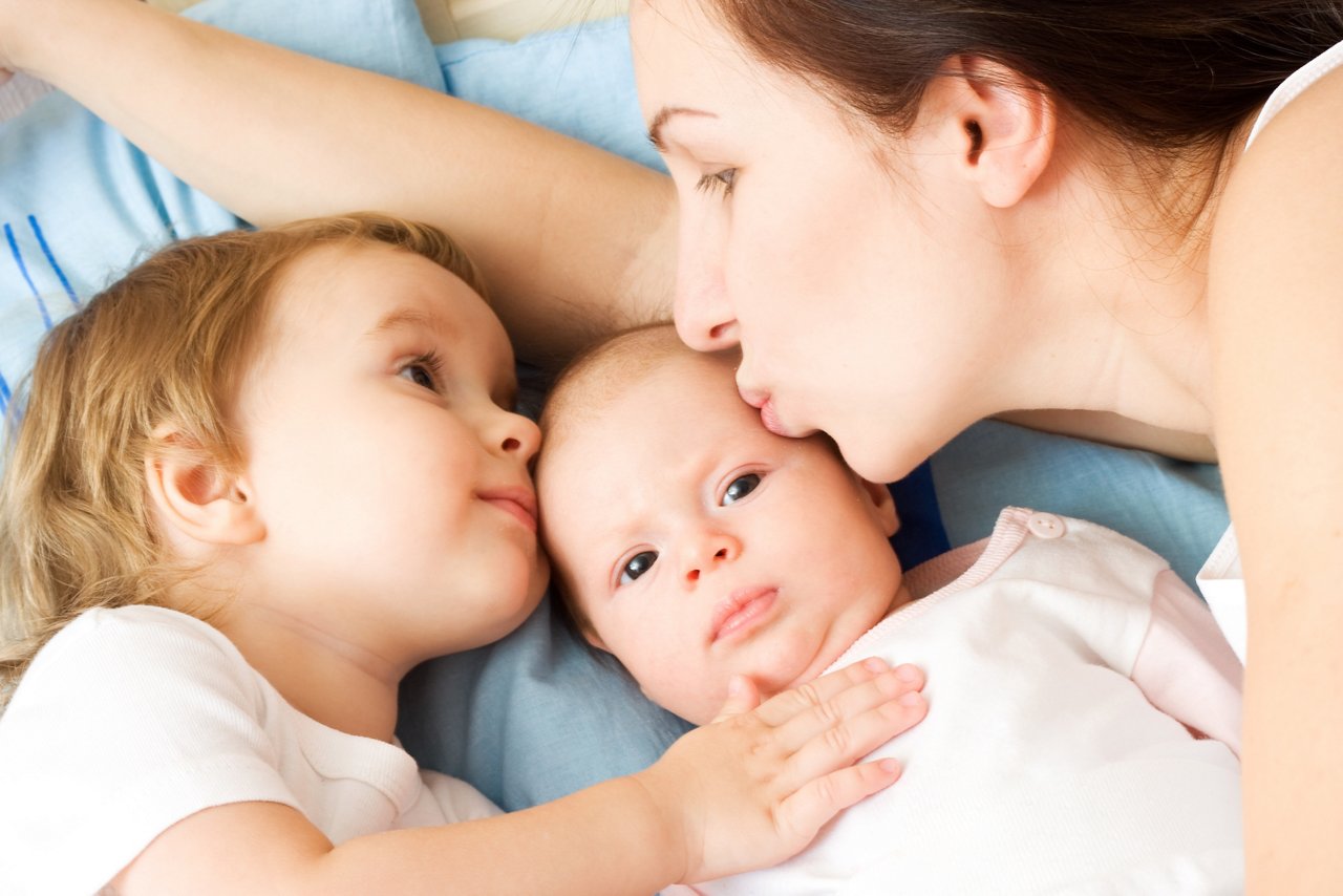 Happy mother with two daughters, kissing and holding them