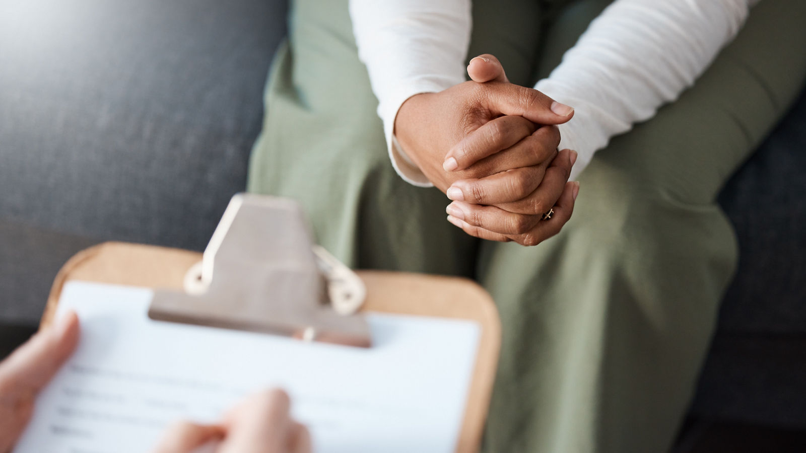 Woman, hands and therapist writing on clipboard in consultation for mental health, psychology or healthcare. Hand of female person or psychologist consulting patient with anxiety or stress in therapy