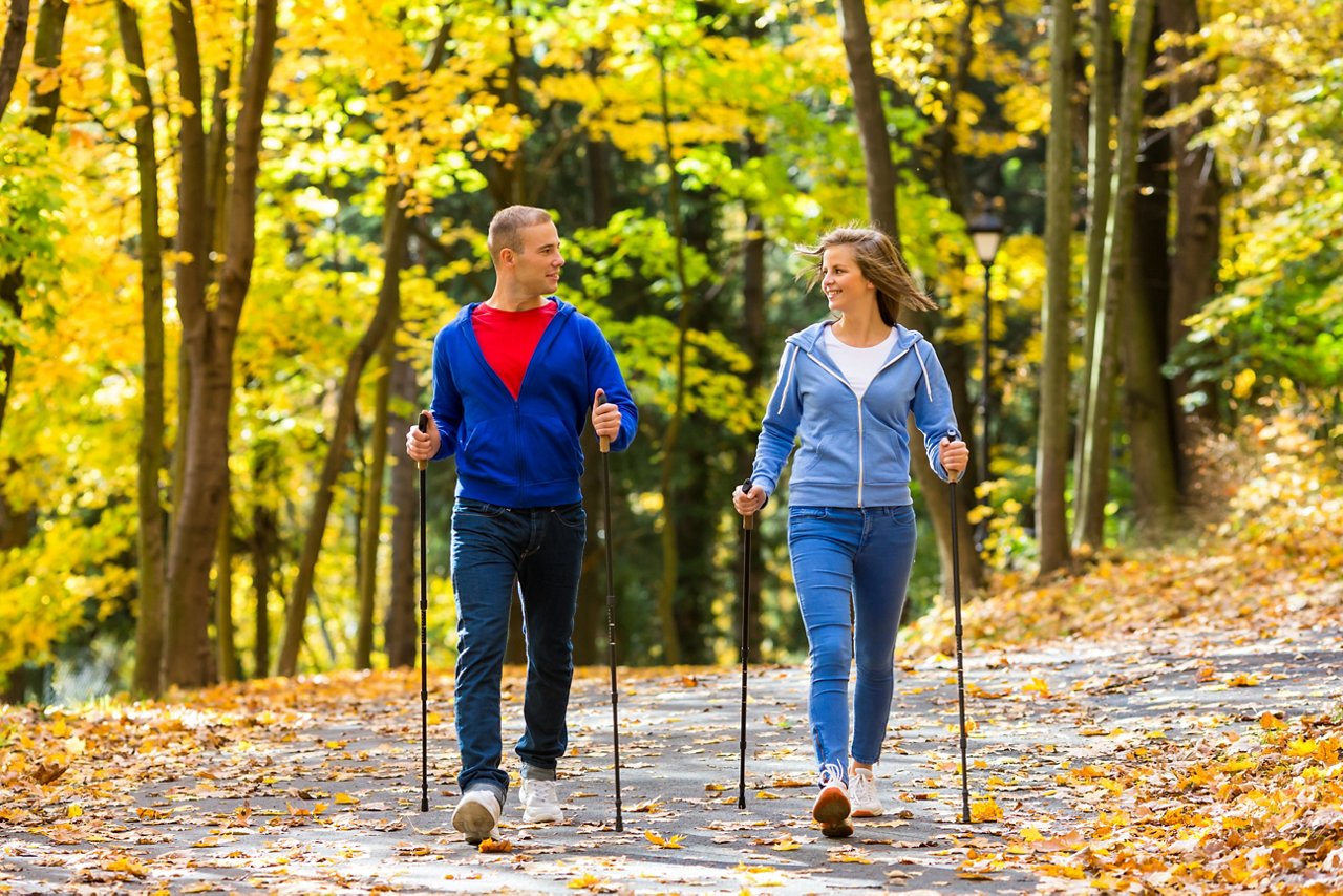 Junger Mann und junge Frau beim Nordic Walking im Wald