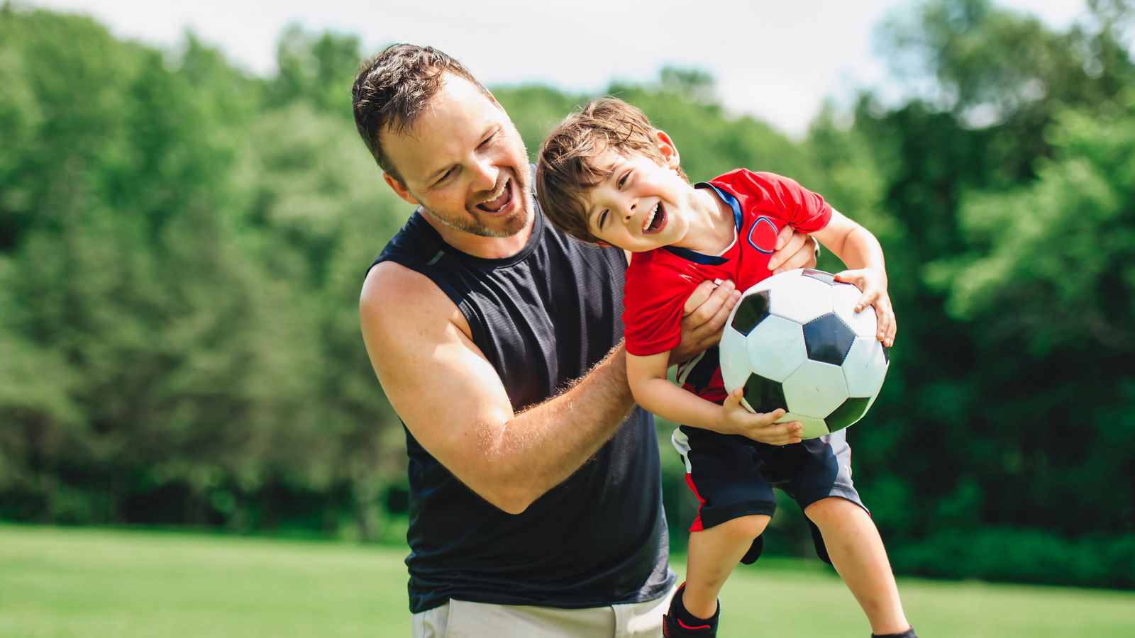 Vater und Sohn spielen miteinander mit Fußball