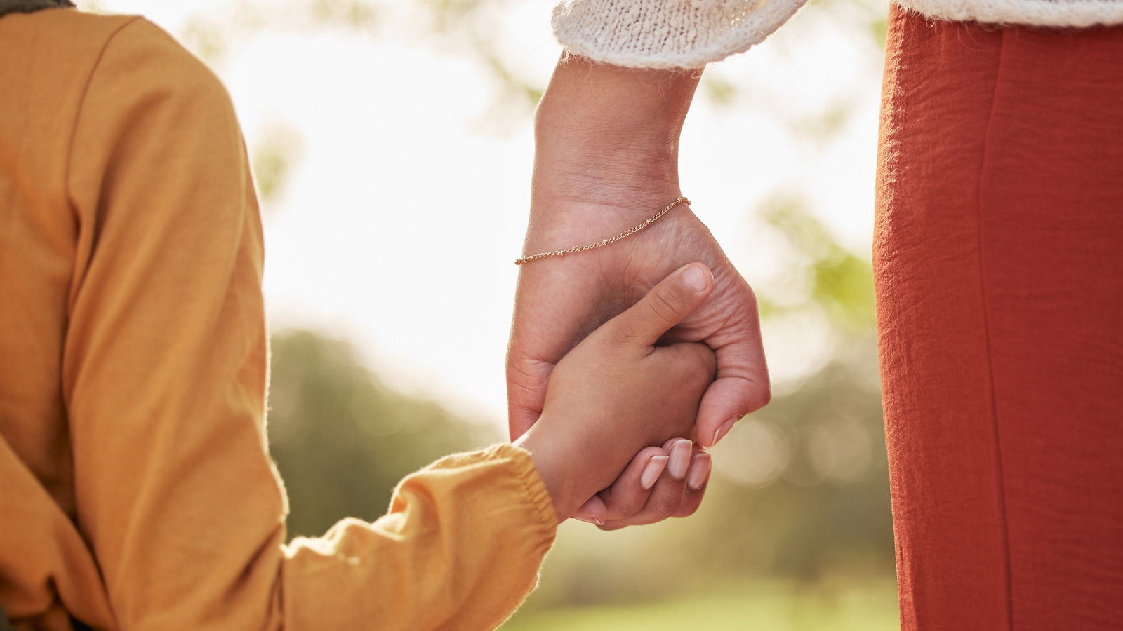 Mother, kid and holding hands for walking in park for support, trust and care together or bonding in nature. Love, comfort and parent help child in the morning sunshine with kindness on weekend