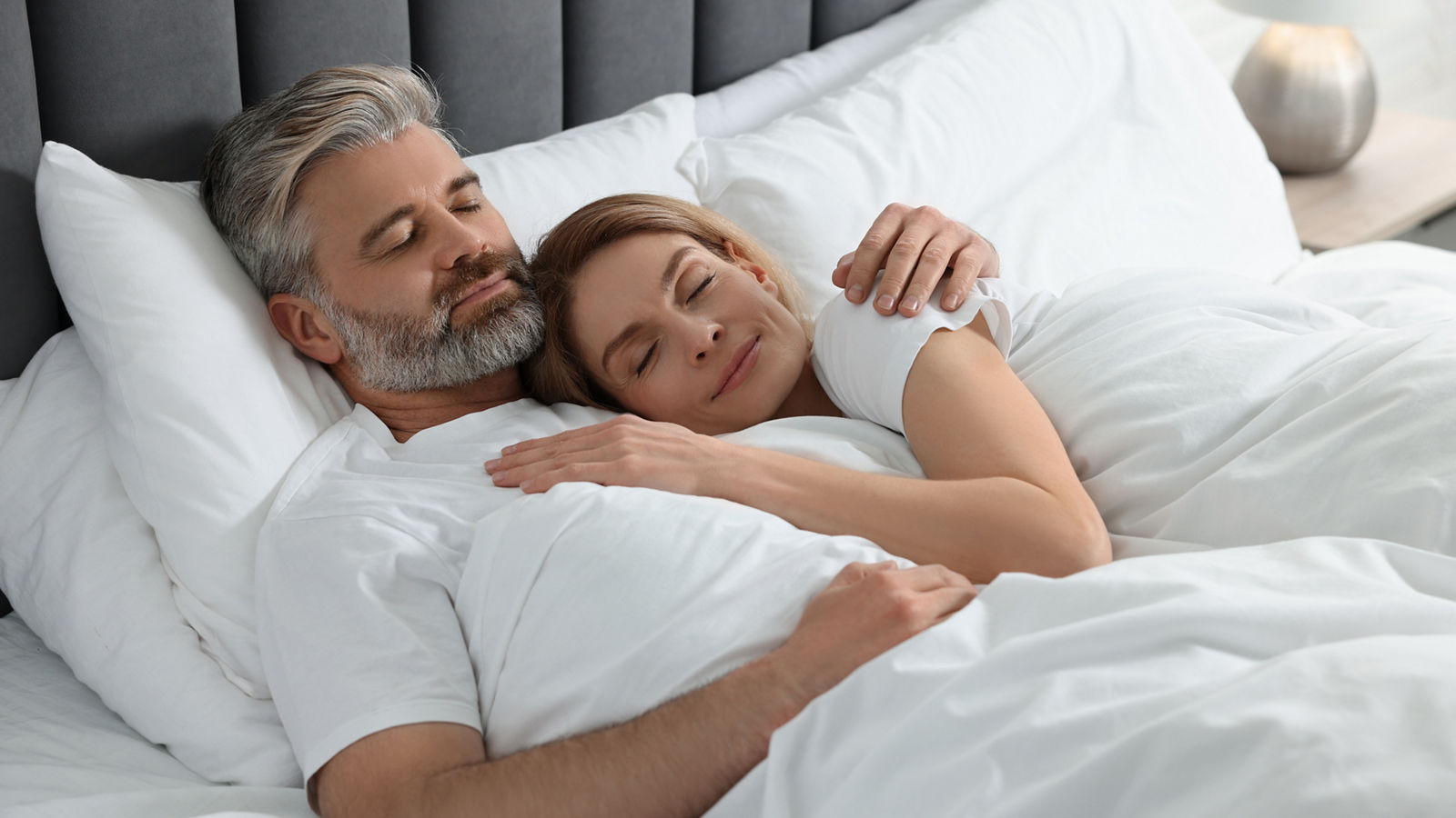 Lovely mature couple sleeping together in bed at home