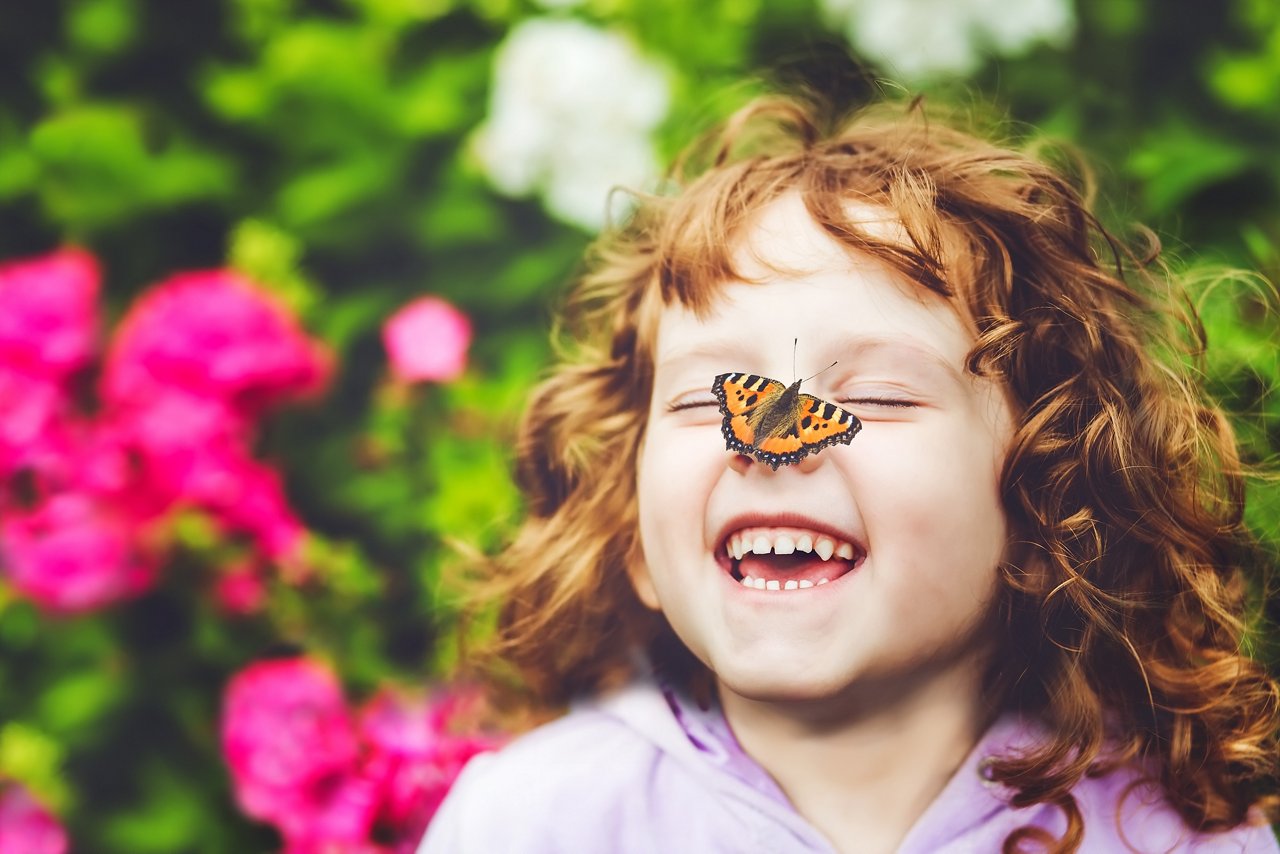 Laughing girl with a butterfly on his nose.