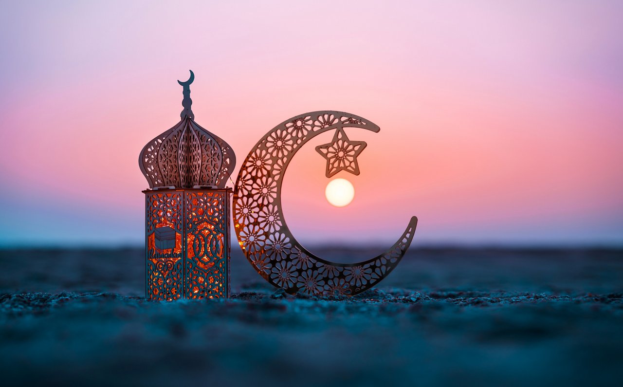 Ramadan Kareem-Fotografie, Laterne in Form einer Mondsichel am Strand vor Sonnenuntergang, Hintergrund für Eid Mubarak-Grüße 2024