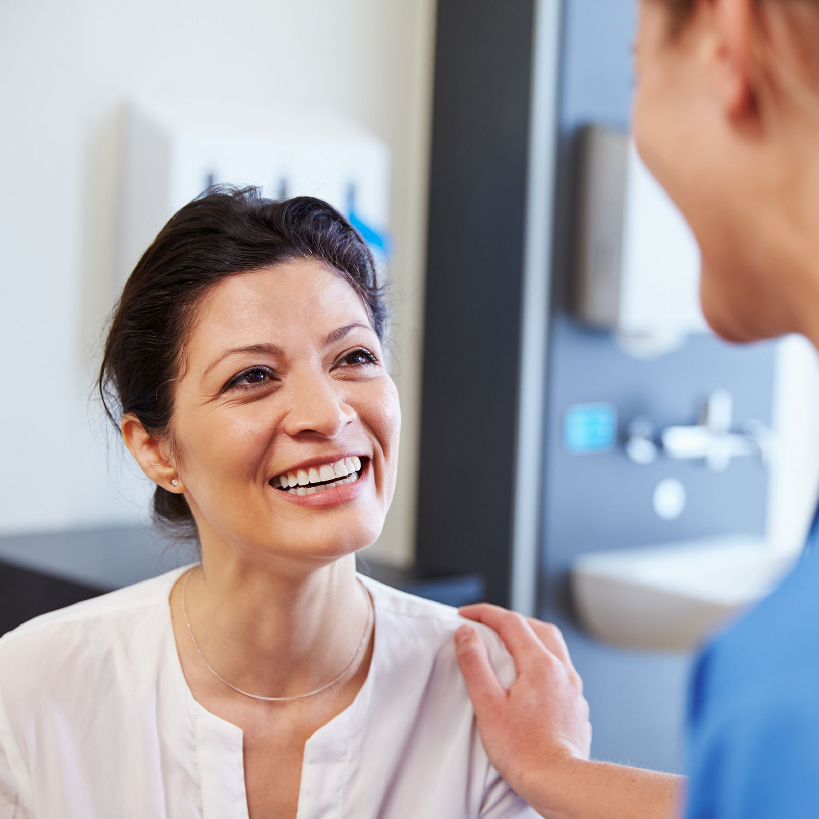 Female Patient Being Reassured By Doctor In Hospital Room