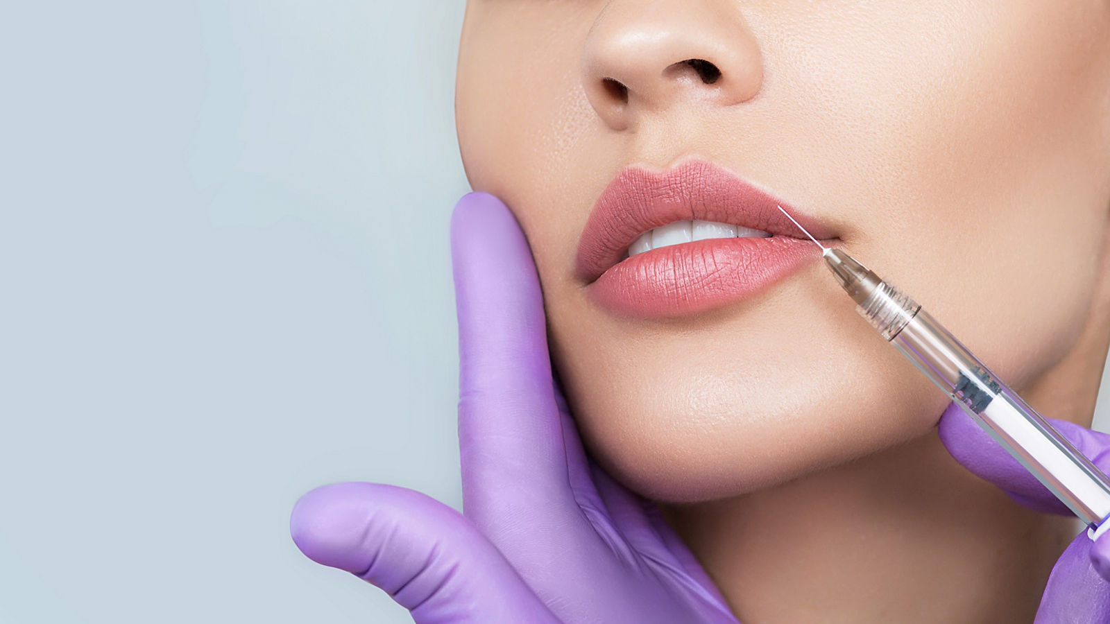 Cropped sensual female lips, procedure lip augmentation. Syringe near womans mouth, injections for increase lips shape