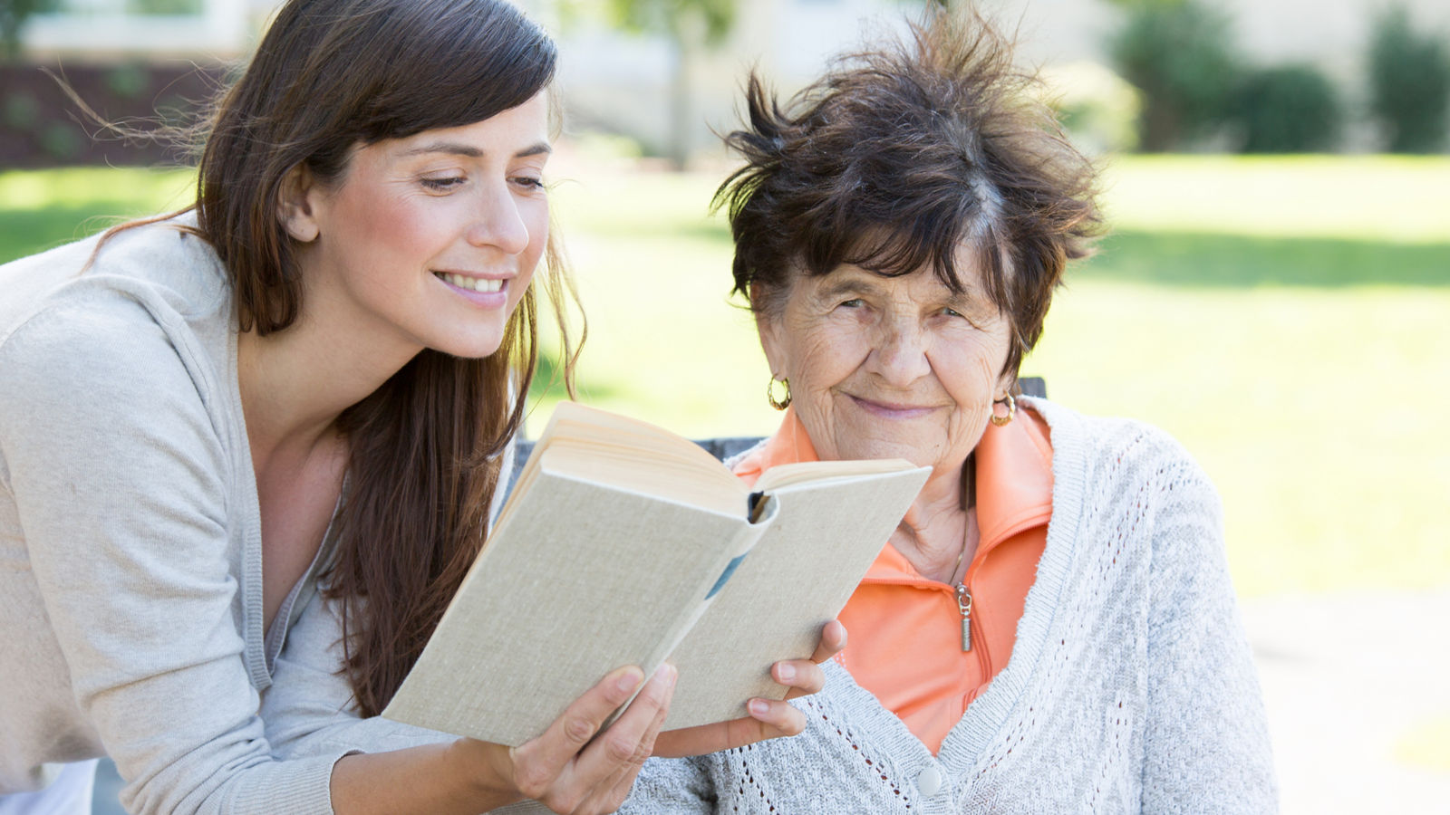 Junge Frau liest Seniorin ein Buch vor