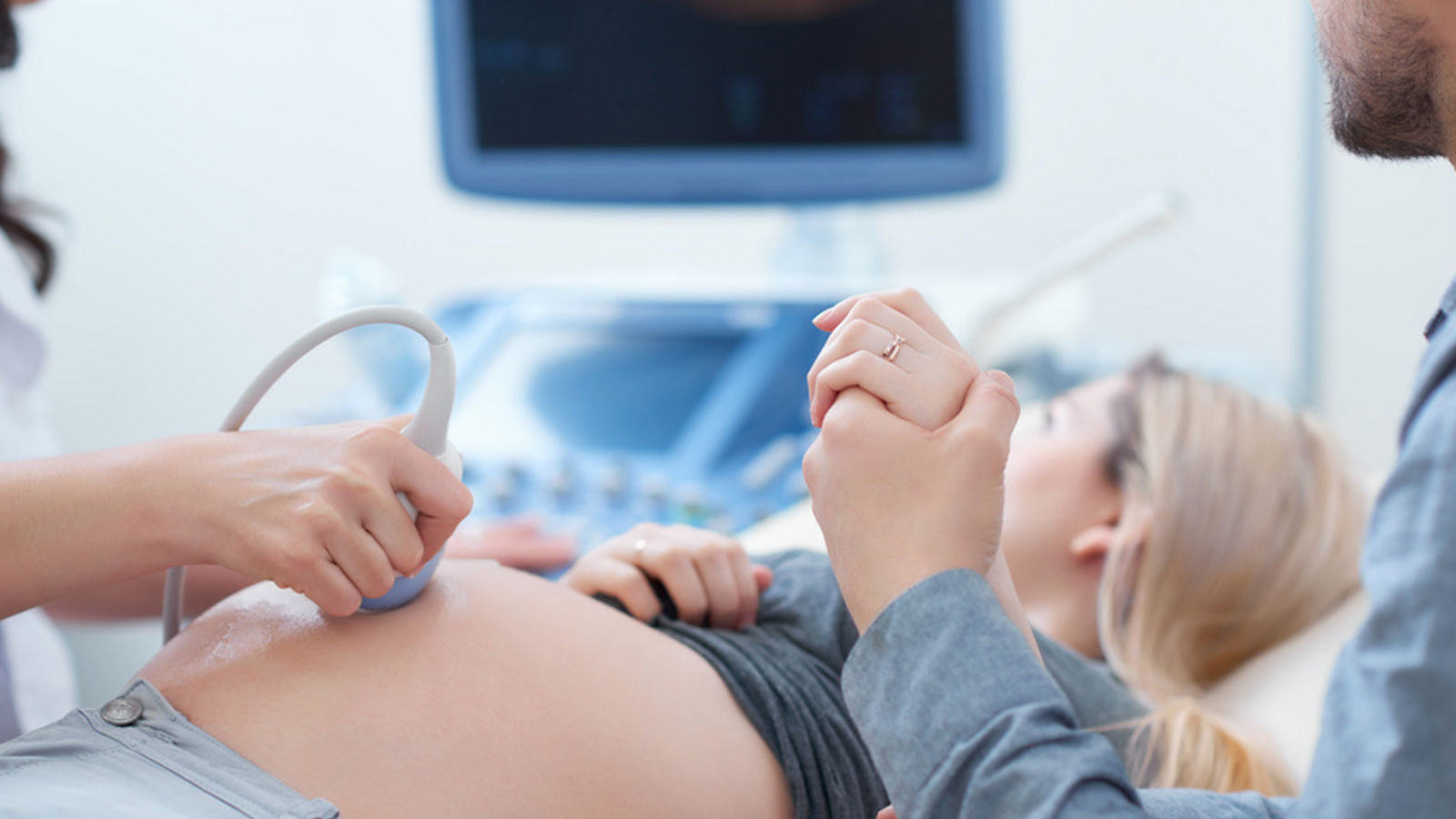 Husband holding hand his wife during ultrasound diagnostic.