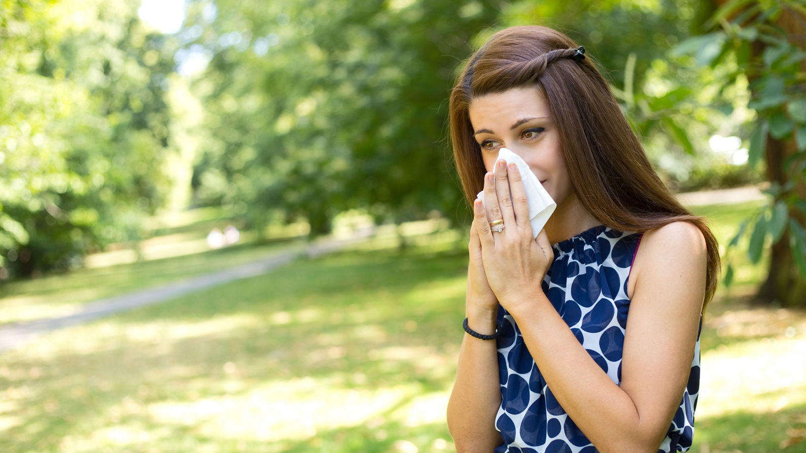 young woman blowing her nose in the park