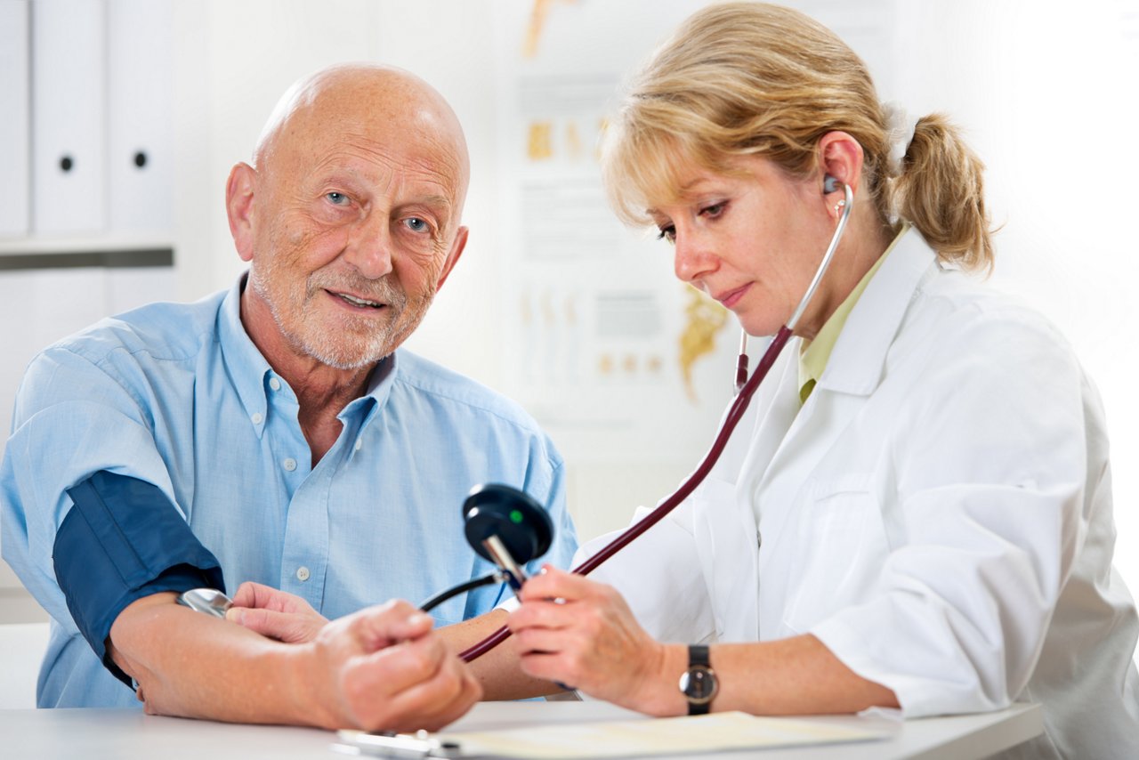 Female doctor measuring blood pressure of senior  man