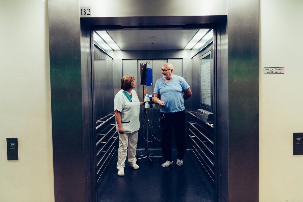 Pflegerin und Patient führen ein Gespräch im Fahrstuhl