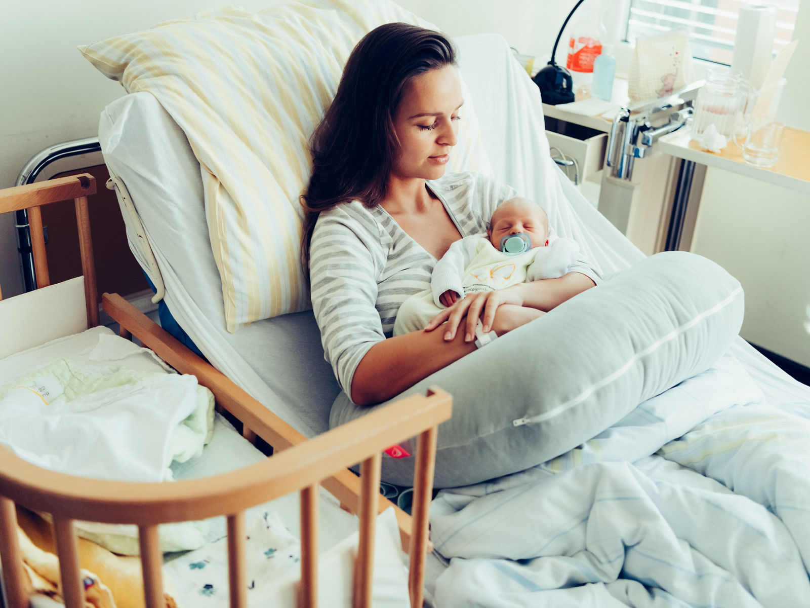 Mutter liegt im Bett und hält ihr Baby im Arm