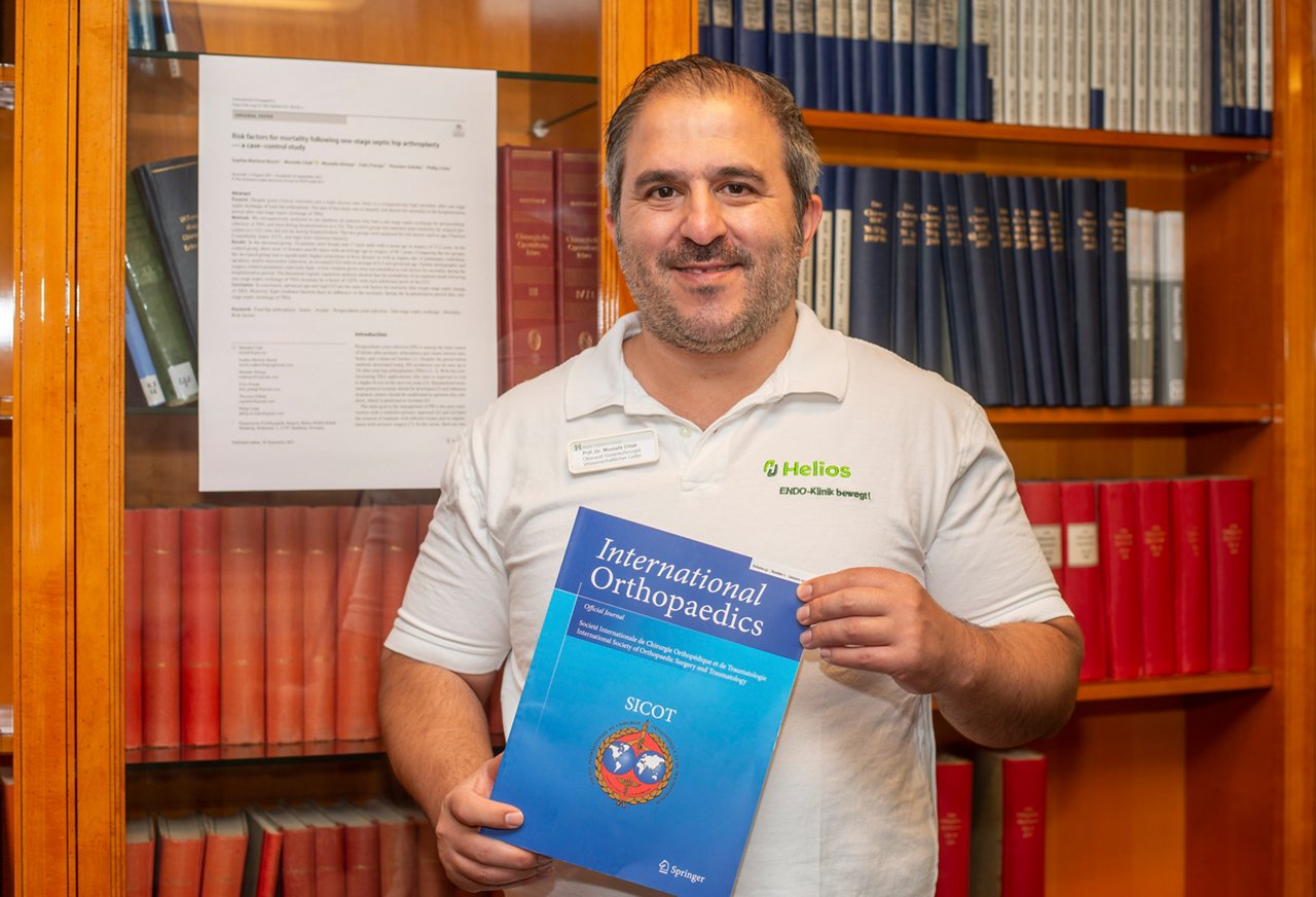 Dr Mustafa Citak in der Bibilothek der ENDO-Klinik Hamburg mit seiner Veröfentlichun im Buch International Orthopaedic