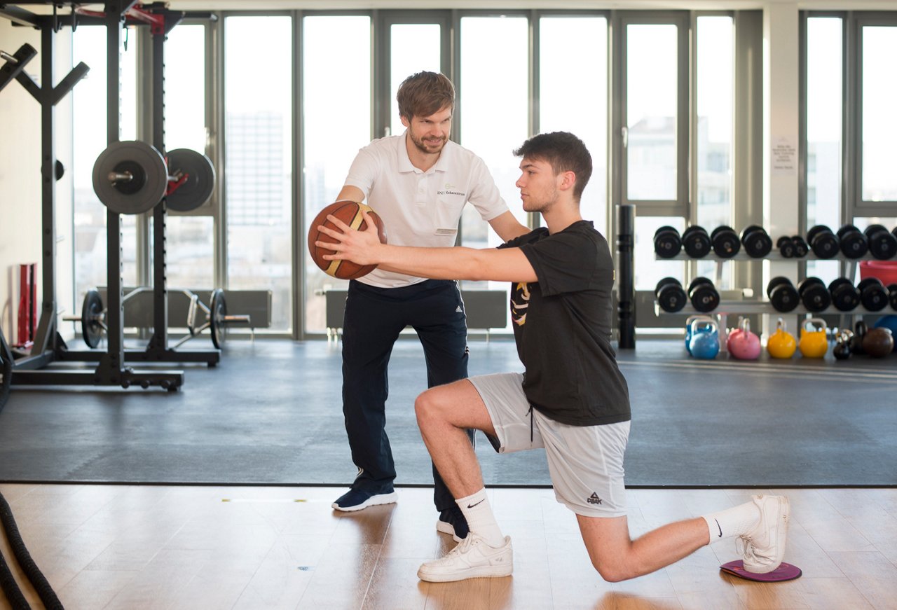 Therapeut mit Basketballspieler, Knieübung