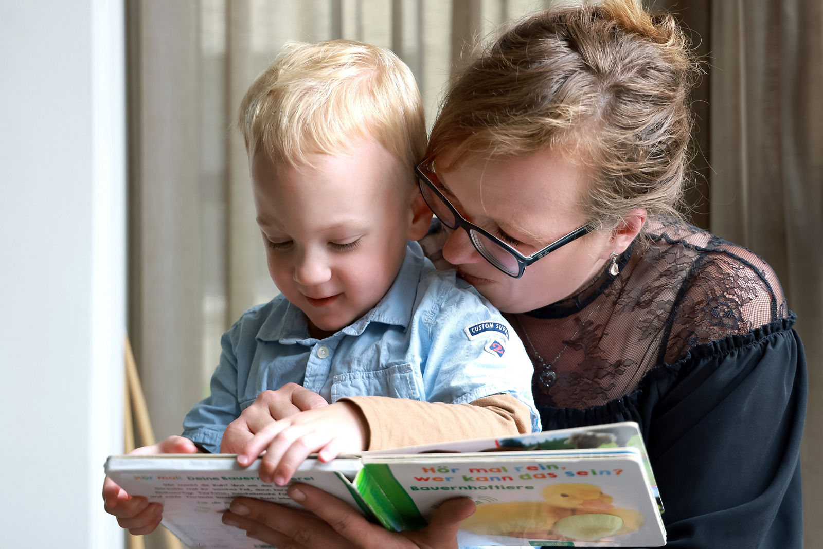 Mutter Selina und Paul lesen gemeinsam ein Buch, Patientengeschichte Paul: Wunderkind mit Kämpferherz, Helios Klinikum Berlin-Buch