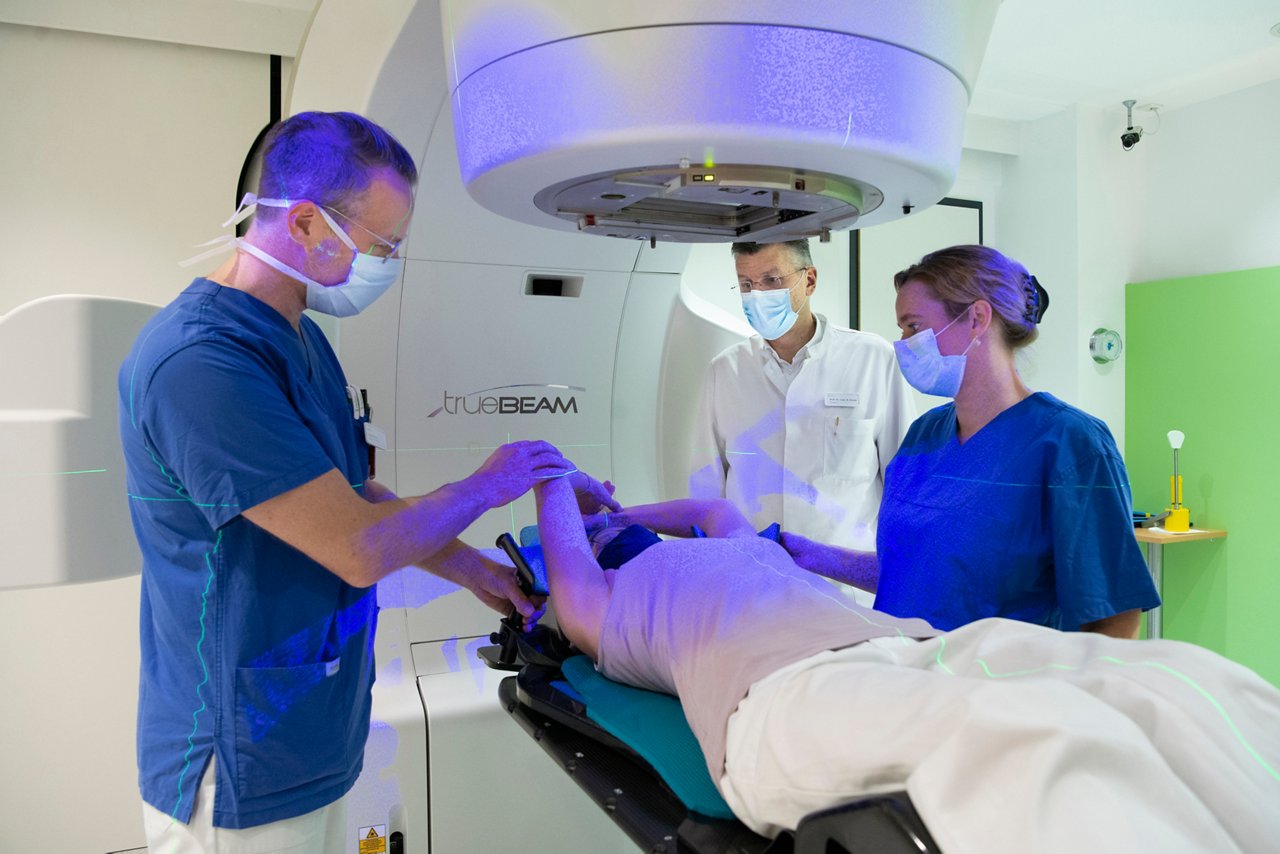 Mitarbeitende der Strahlentherapie positionieren eine Patienten unter dem Bestrahlungsgerät