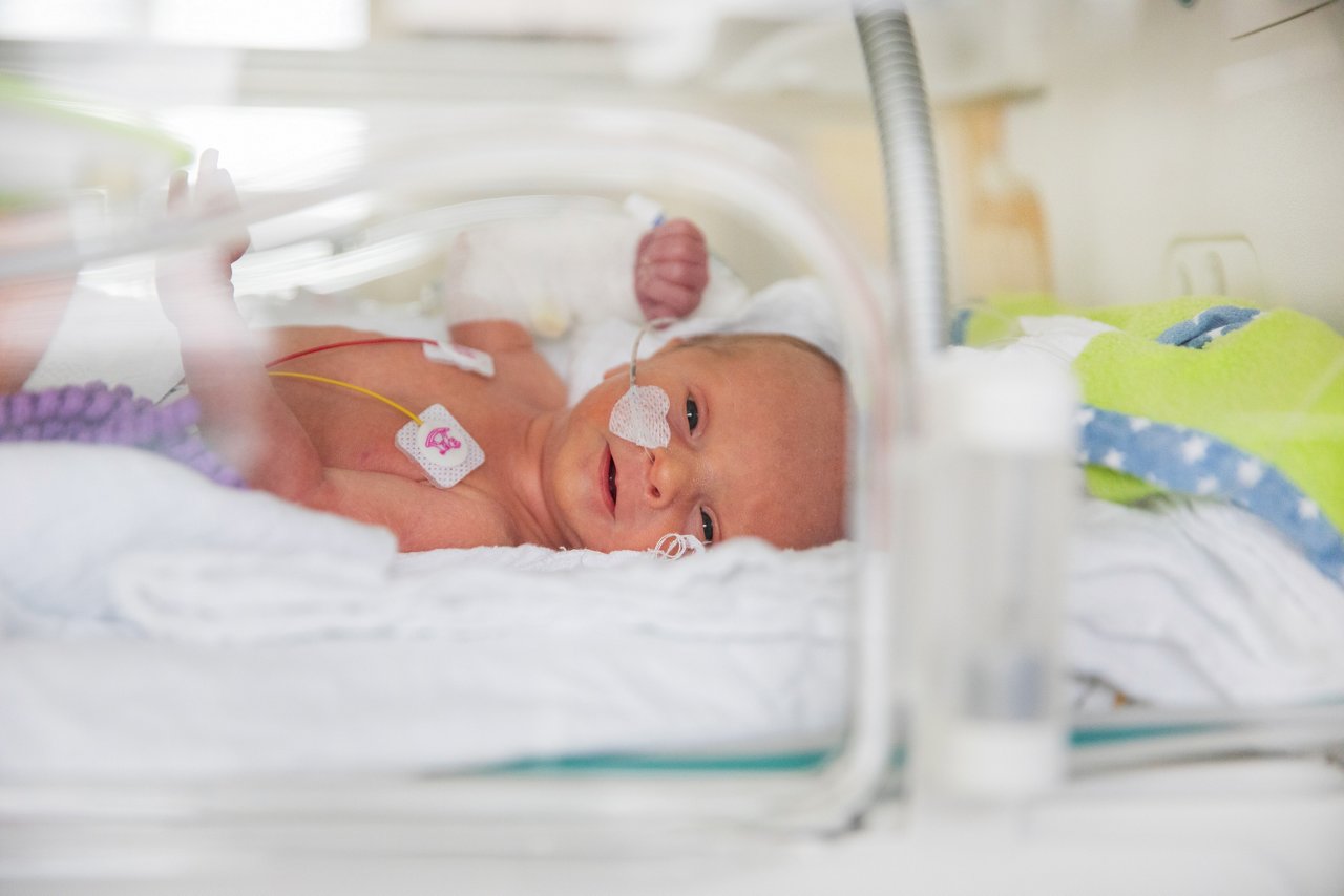Frühchen liegt lächelnd im Inkubator