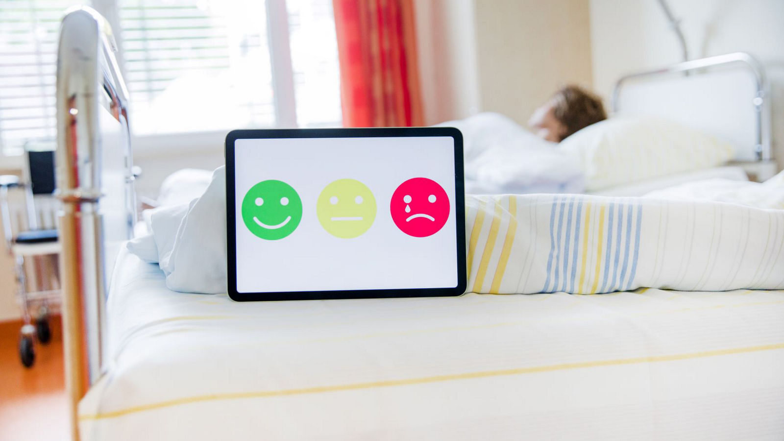 Tablet mit Smileys auf einem Patientenbett